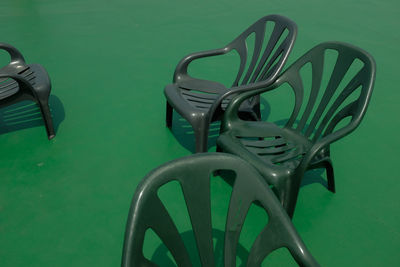 High angle view of empty plastic chairs on green floor