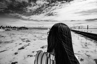 Rear view of woman on beach against sky