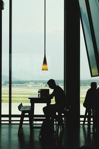 Silhouette man sitting on table in cafe