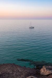 Tranquil sunrise over the ocean with a  sailboat and a palm