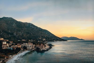 Scenic view of sea by town against sky during sunset