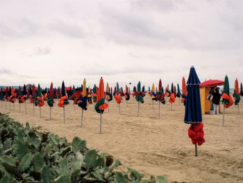 Multi colored flags on beach against sky