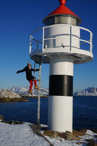 Full length of woman standing by lighthouse on snow covered mountain