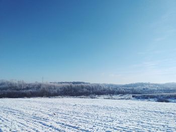 Snow covered field against blue sky