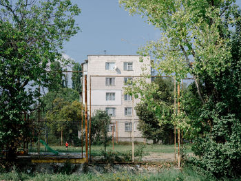 Trees by building against sky