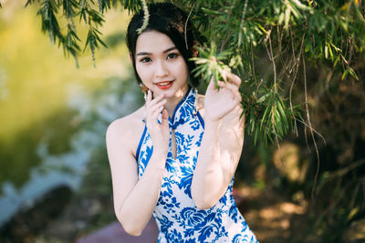 Portrait of young woman standing amidst plants