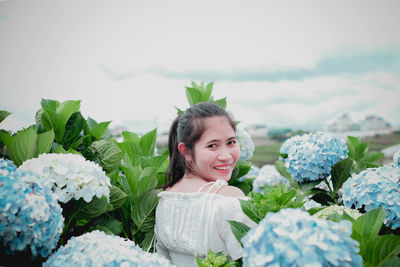 Portrait of smiling young woman against plants