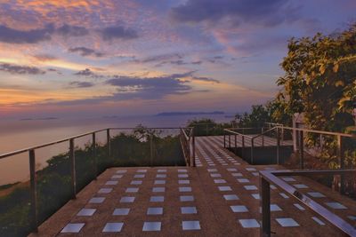 Footpath amidst trees against sky during sunset