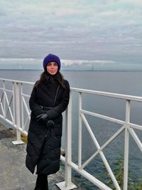 Portrait of young woman standing against sea