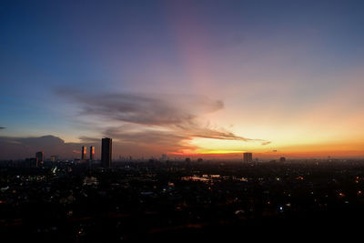 Illuminated cityscape against sky during sunset