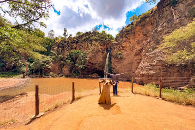 A man standing next to a waterfall at makalia waterfall in lake nakuru national park in kenya