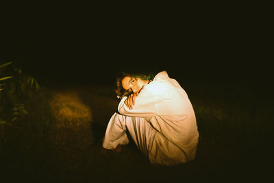 Side view of young woman on field at night