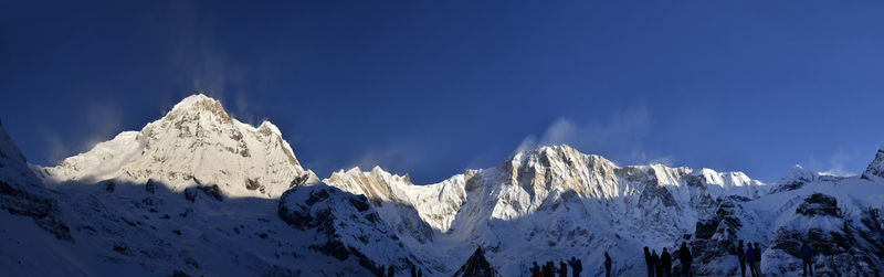 Scenic view of snow covered mountains against blue sky