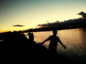 Silhouette man standing by sea against sky during sunset