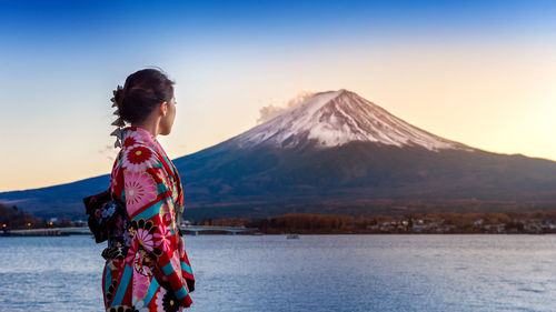 Side view of woman in kimono standing against mt fuji during winter