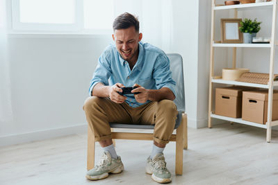 Portrait of young man sitting on chair at home