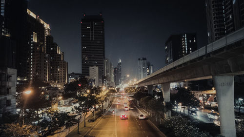 City street amidst illuminated buildings against sky at night