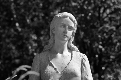 Portrait of young woman against blurred trees