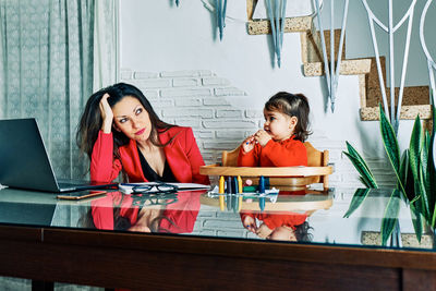 Young executive woman tired of working at home with her young daughter