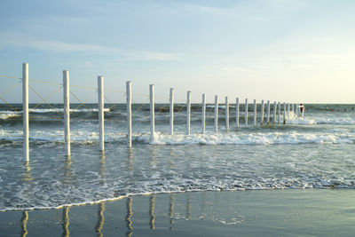 Wooden posts on beach against sky