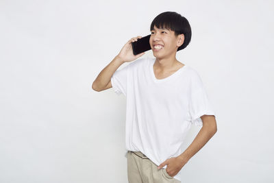 Smiling young woman standing against white background