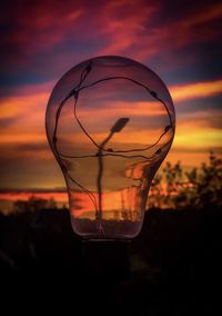 Close-up of glass against orange sunset sky