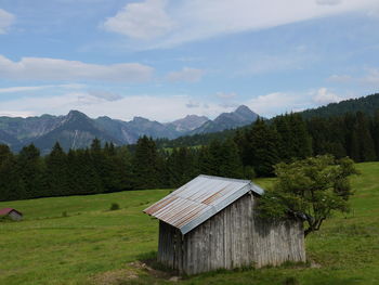 An old barn in the mountains by trees against sky