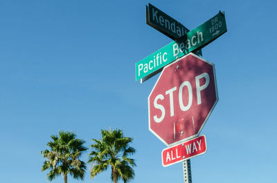 Low angle view of road signs against clear blue sky