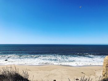 Scenic view of beach against clear blue sky