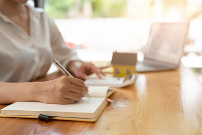 Midsection of lawyer writing in book