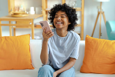 Young woman using mobile phone while lying on bed at home