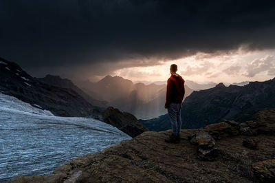 Rear view of man standing on mountain against sky