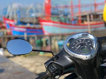 Dashboard of motor scooter against boats moored at harbor