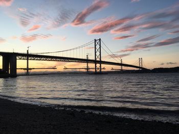 Forth road bridge over sea against sky during sunset