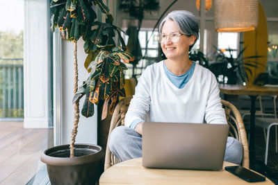 Portrait of young woman using laptop at table