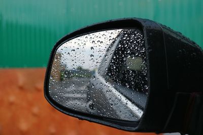 Close-up of raindrops on side-view mirror