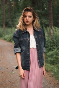 Portrait of woman standing in forest against trees