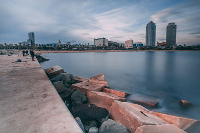 City by river and buildings against sky