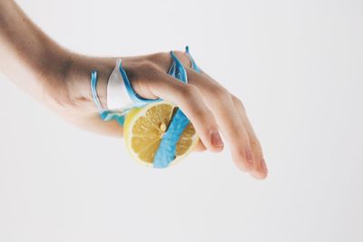 Close-up of hand holding fruit over white background