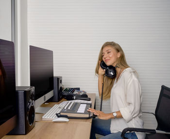 Young woman listening music while sitting at recording studio