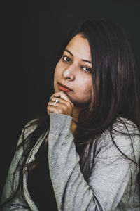 Close-up of young woman against black background