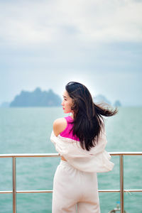 Side view of young woman looking away against sky