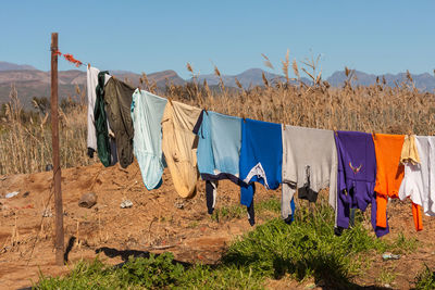 Clothes drying on field against clear sky