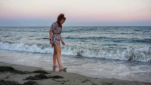 Full length of woman standing on beach against sky