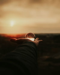 Person holding umbrella against sky during sunset