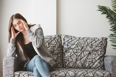 Young woman sitting on sofa at home