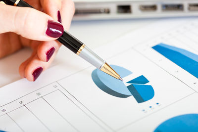 Close-up of businesswoman holding pen against data on paper