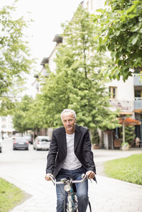 Portrait of mature businessman riding bicycle on street