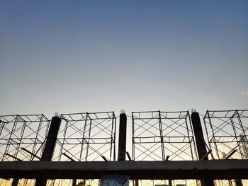 Low angle view of silhouette metal fence against sky