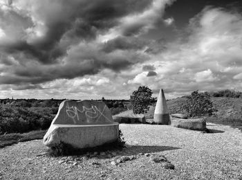 Trees on landscape against cloudy sky